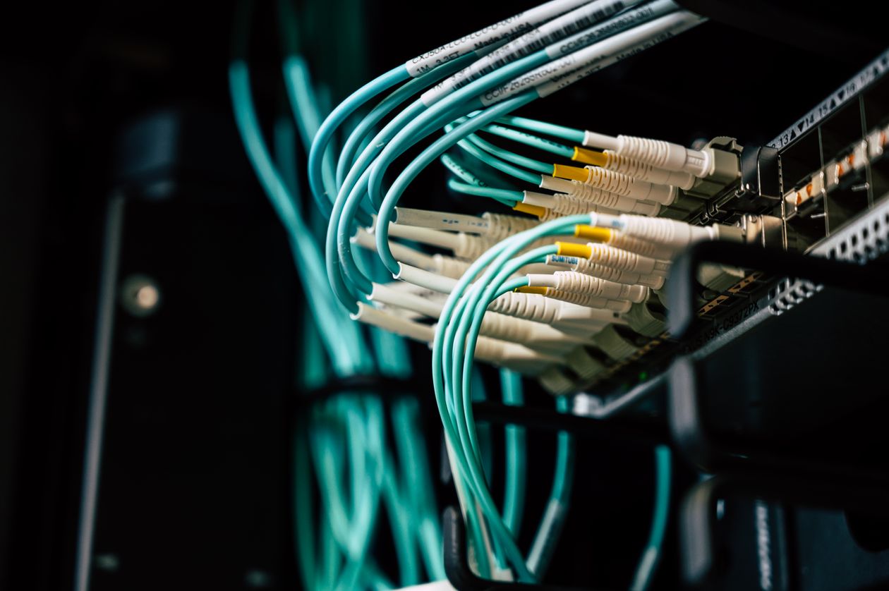 Fiber optic cables connected to network equipment in a dark rack, illustrating enterprise network security